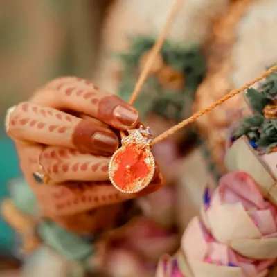 A close-up of the bride holding the sacred thali or mangalsutra. This shot highlights a deeply symbolic and emotional part of the wedding ceremony.