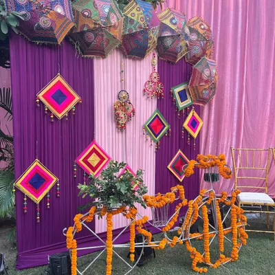 A quirky and colorful Mehndi corner, featuring a bicycle adorned with marigolds and a backdrop of Rajasthani umbrellas and hangings.
