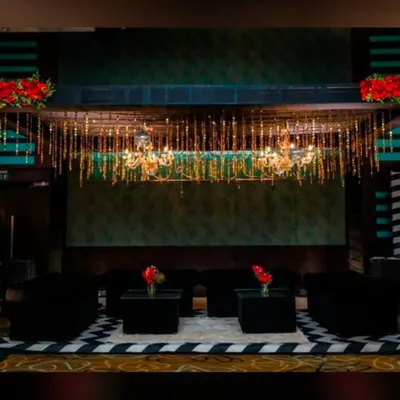 A chic lounge area we created for a corporate event, featuring modern black furniture and a stunning overhead installation of chandeliers and hanging golden tassels. This setup provides a comfortable and stylish space for guests to connect.
