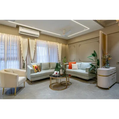 A full view of a modern living room designed for comfort and style. The neutral color palette is accented with pops of color from the cushions, while the elegant curtains and wall mouldings add a layer of sophistication.