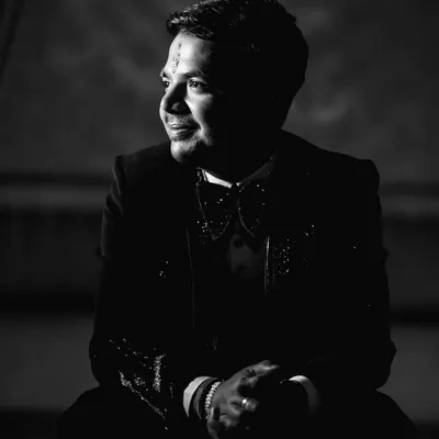 A dramatic black and white groom portrait. Using strong shadows and light (chiaroscuro), this image creates a moody and sophisticated look, highlighting the groom's features in a very cinematic style.