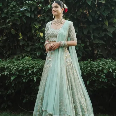 A vision in pastel. Our bride radiates pure joy, adorned in a magnificent uncut polki diamond and pearl choker set that perfectly complements her serene mint green lehenga for her daytime wedding ceremony.