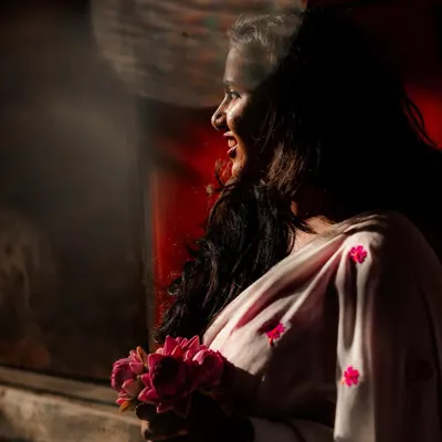 A bride-to-be holds a bouquet of lotuses, her smile illuminated by a ray of sunlight. This shot is from a pre-wedding series we did on the old streets of Bengaluru.