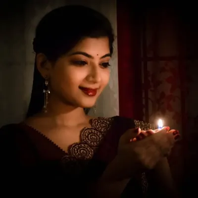 A heartfelt portrait for Deepavali, holding a small diya. The low-light photo creates an intimate and warm atmosphere, focusing on the theme of love and light.