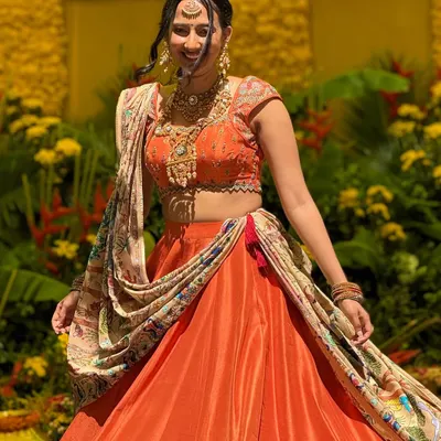 This bride is glowing in a custom orange silk lehenga. The skirt features a hand-painted border, and I paired it with a fully Kashmiri embroidered georgette dupatta and a matching embroidered blouse for a vibrant, celebratory look.