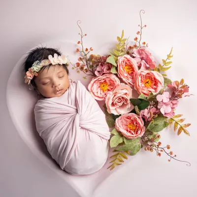 A little flower child, nestled in a heart and surrounded by pink blossoms. We use props like this heart-shaped bowl to create artistic and beautiful newborn portraits.