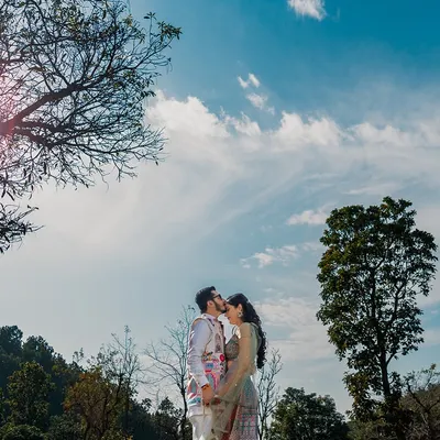 A kiss under the vast blue sky, surrounded by the mountains. This wide-angle shot captures the epic scale of nature, making their intimate moment feel even more special.