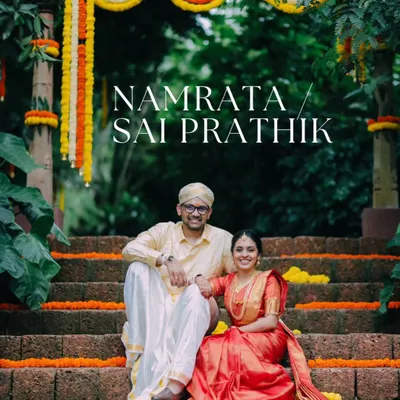 A classic portrait of Namrata and Sai Prathik at The Peacock Grove, surrounded by traditional marigold decor. This shot captures the timeless elegance of a South Indian wedding.