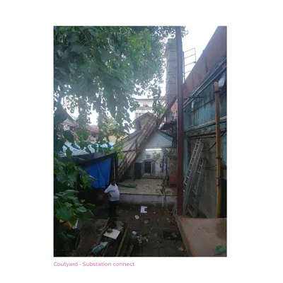 The courtyard of the Ambico Ice Factory before our intervention. This image documents the cluttered state, with ad-hoc structures choking the banyan tree and obscuring the building's original connection to the street.