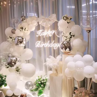 An ethereal and dreamy all-white birthday theme. This setup features a beautiful white balloon arch, a sheer curtain backdrop, a neon sign, and delicate floral accents for a truly elegant and sophisticated celebration.