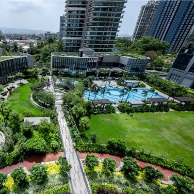 An aerial view of a lush residential development, showcasing the integration of a large central lawn, swimming pool, and extensive green roofs. Our designs transform high-density projects into green, livable communities where residents can connect with nature.