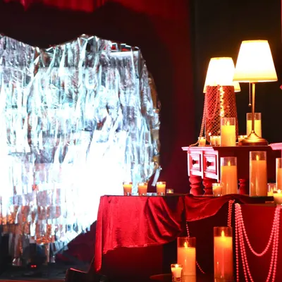 A cozy and dramatic corner from the 'Scarlet Splendor' event, featuring a crushed silver foil backdrop, red velvet, and an abundance of candles.
