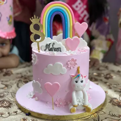 A magical unicorn and rainbow cake for an 8th birthday. This cake features a cute, hand-sculpted fondant unicorn, fluffy clouds, and a colorful rainbow topper.