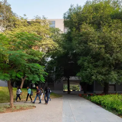 The campus of Ahmedabad University is designed as a seamless extension of its verdant landscape. Walkways and buildings are carefully sited among existing trees, creating a pedestrian-friendly environment that encourages movement and connection with nature.