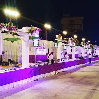 A grand buffet line under the stars, featuring elegant white counters with vibrant purple skirting. This setup is designed for large-scale weddings, ensuring a smooth flow for guests while adding a touch of color and sophistication to the evening.