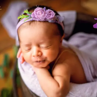 A sweet smile from a sleeping baby, nestled in a bucket with a lavender wrap and floral headband. I love coordinating colors to create a harmonious and artistic portrait.