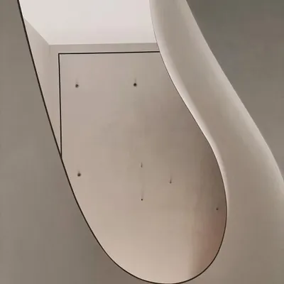 The sweeping curve of the Worli Duplex staircase, viewed from below. The abstract, sculptural quality of the form is revealed by the way it catches and reflects light, creating a fluid, organic shape within the home.