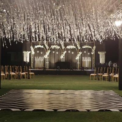 A stunning sangeet night setup featuring a custom chevron-patterned dance floor and a shimmering tinsel canopy, ready for an evening of performances.
