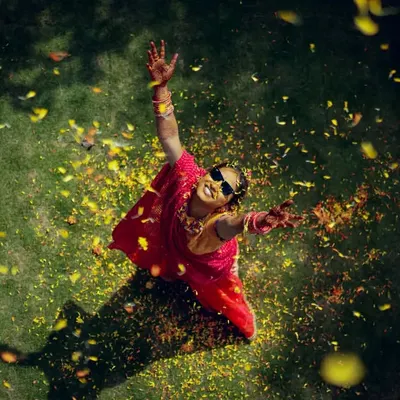 An aerial shot of the bride celebrating her Haldi, throwing petals in the air with pure joy. We use creative angles to capture the energy of the event.