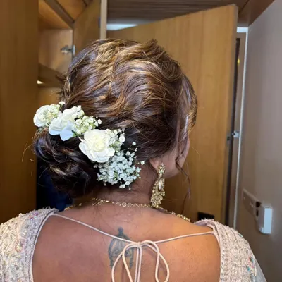 A detailed shot of a beautiful floral bridal bun. The combination of white roses and baby's breath adds a touch of romance and elegance to this classic hairstyle.