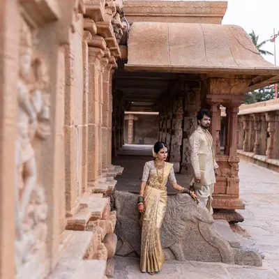 A majestic portrait of a couple in traditional South Indian attire at a heritage temple site, blending their love story with timeless culture.