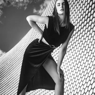 A bold black and white portrait that plays with architectural patterns and strong diagonal lines. The high contrast and the model's powerful pose create a striking and modern composition.