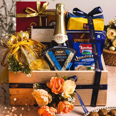 A luxurious gourmet hamper perfect for celebrations, featuring sparkling wine, Castello cheese, and premium snacks. Presented in a signature wooden crate with floral details, this is an ideal gift for Diwali or as a high-end wedding favour.