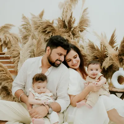 A quiet, tender moment with a family and their newborn twins. The neutral tones and soft textures of the boho setup create a serene atmosphere for this beautiful family portrait.