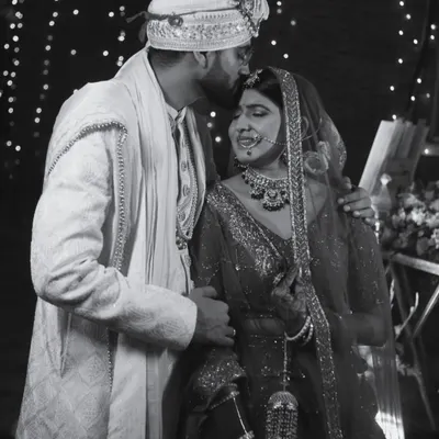 A tender black and white moment between the couple. The groom's kiss on the bride's forehead is a timeless expression of love.