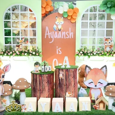 A full view of the woodland jungle theme for Ayaansh's first birthday. This large scale decoration features a custom backdrop, adorable animal figures like a deer and fox, and organic balloon garlands.