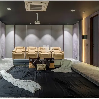 A full view of our custom home theater, designed for the ultimate cinematic experience. The room features plush leather recliners for premium seating, complemented by a large, informal dug-out area in the front for casual lounging.