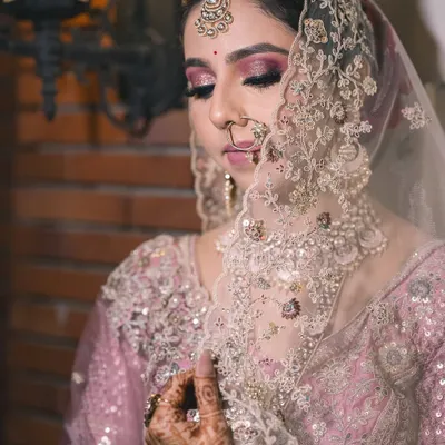 A serene moment as the bride adjusts her veil. I love capturing these quiet, reflective shots that highlight the intricate details of the bridal look, from the makeup to the embroidery.