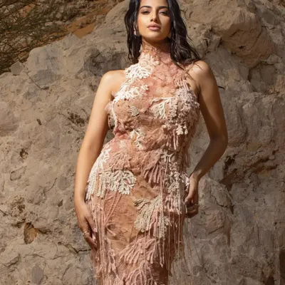 A stunning shot from a desert editorial, where the textured, earth-toned gown blends beautifully with the natural rock formations. This is an example of location-based storytelling.