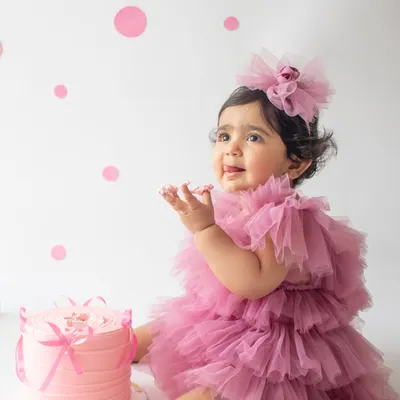 A first birthday is a huge milestone, and a cake smash is the perfect way to celebrate. This little one is having the best time with her very own pink cake in a clean, minimalist setup.
