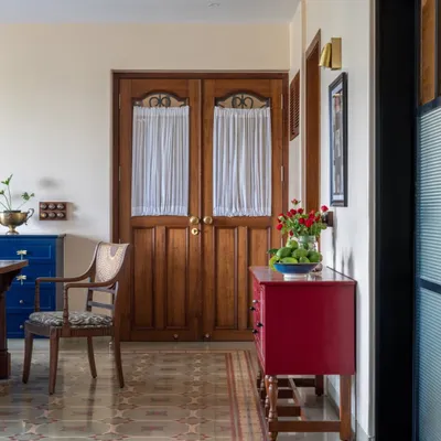 This Calcutta living room was designed to hold a family's energy and memories. We kept the soul of their old bungalow by using warm woods, patterned heritage tiles, and pops of color like this red console. The goal was to create a space that feels generous and grounded, where stories can be passed down for generations.