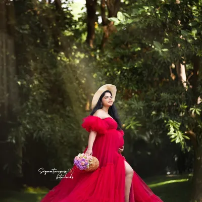 A fairytale moment in the woods. The flowing red gown and sun-dappled light create a truly magical outdoor maternity portrait.
