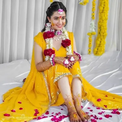 A radiant bride during her haldi ceremony, with her beautiful bridal mehendi on her hands and feet adding to her glow.