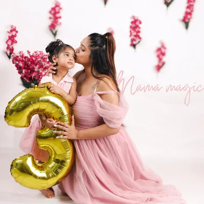 A tender moment between a mother and her daughter celebrating her third birthday. The golden '3' balloon marks the special occasion in this beautiful studio portrait.