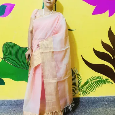 Dressed in a beautiful peach and gold tissue saree for Durga Puja. This full-length shot against a colorful painted wall highlights the elegance of the attire.