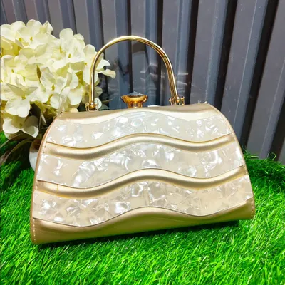 This elegant gold and mother-of-pearl clutch with a wavy design is a unique piece that will elevate any outfit. It's perfect for holding your essentials at a wedding.
