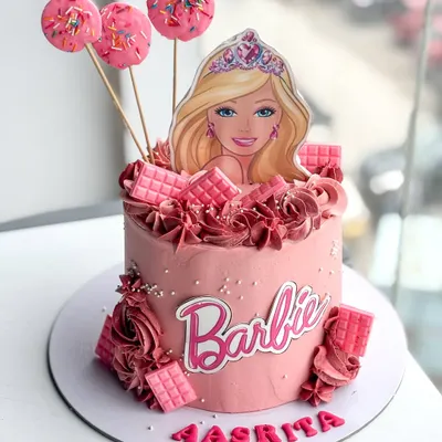 Come on Barbie, let's go party! This vibrant pink Barbie-themed cake is a dream for any fan. It's a buttercream cake decorated with a Barbie topper, pink chocolate bars, and matching cake pops, perfect for a fun and stylish birthday party.