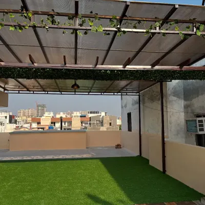 A spacious terrace converted into a usable outdoor lounge. I installed soft artificial grass and decorated the pergola beams with artificial ivy to create a relaxing, shaded environment.