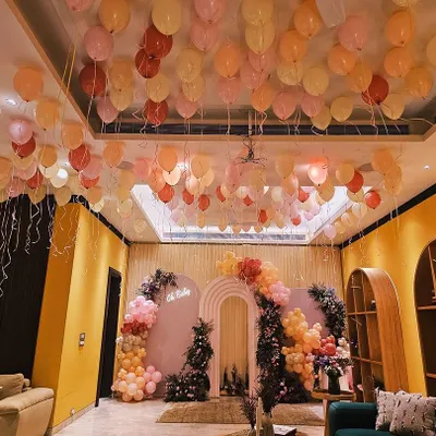 A baby shower that's blooming with love. This gorgeous setup features a pastel balloon arch, lush floral arrangements, and a ceiling filled with floating balloons, creating a dreamy and welcoming space for the mom-to-be.