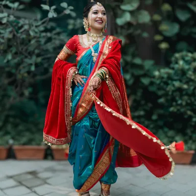 A full-length portrait of a stunning Marathi bride, showing off the beautiful drape of her traditional Nauwari saree and red velvet shawl.