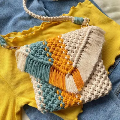 I'm in love with this color combination! 💛 This yellow, teal, and cream macrame sling bag has such a fresh and happy vibe. It's styled as a crossbody bag here, showing off the detachable strap and fringe detail on the flap. It’s the perfect accessory for a sunny day out.