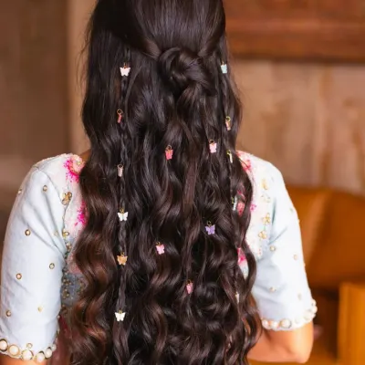 This beautiful, long, and wavy hairstyle was created using clip-in extensions. The added butterfly clips make it a perfect look for a festive or special occasion.