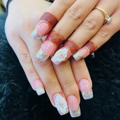 The perfect bridal nails, featuring a classic French manicure with silver glitter, gold accents, and stunning 3D flowers.
