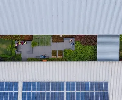 This aerial view of a factory extension shows my commitment to energy efficiency, with integrated solar panels and a green roof. The central courtyard is a landscaped breakout space, improving the indoor environment for workers.