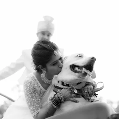 A heartwarming black and white photo of the bride kissing her happy dog. A beautiful, candid moment showing that pets are family too.