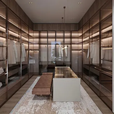 A view of the spacious walk-in closet, featuring floor-to-ceiling glass wardrobes with integrated lighting. The central island provides additional storage and a surface for organizing, while the plush bench adds a touch of comfort.